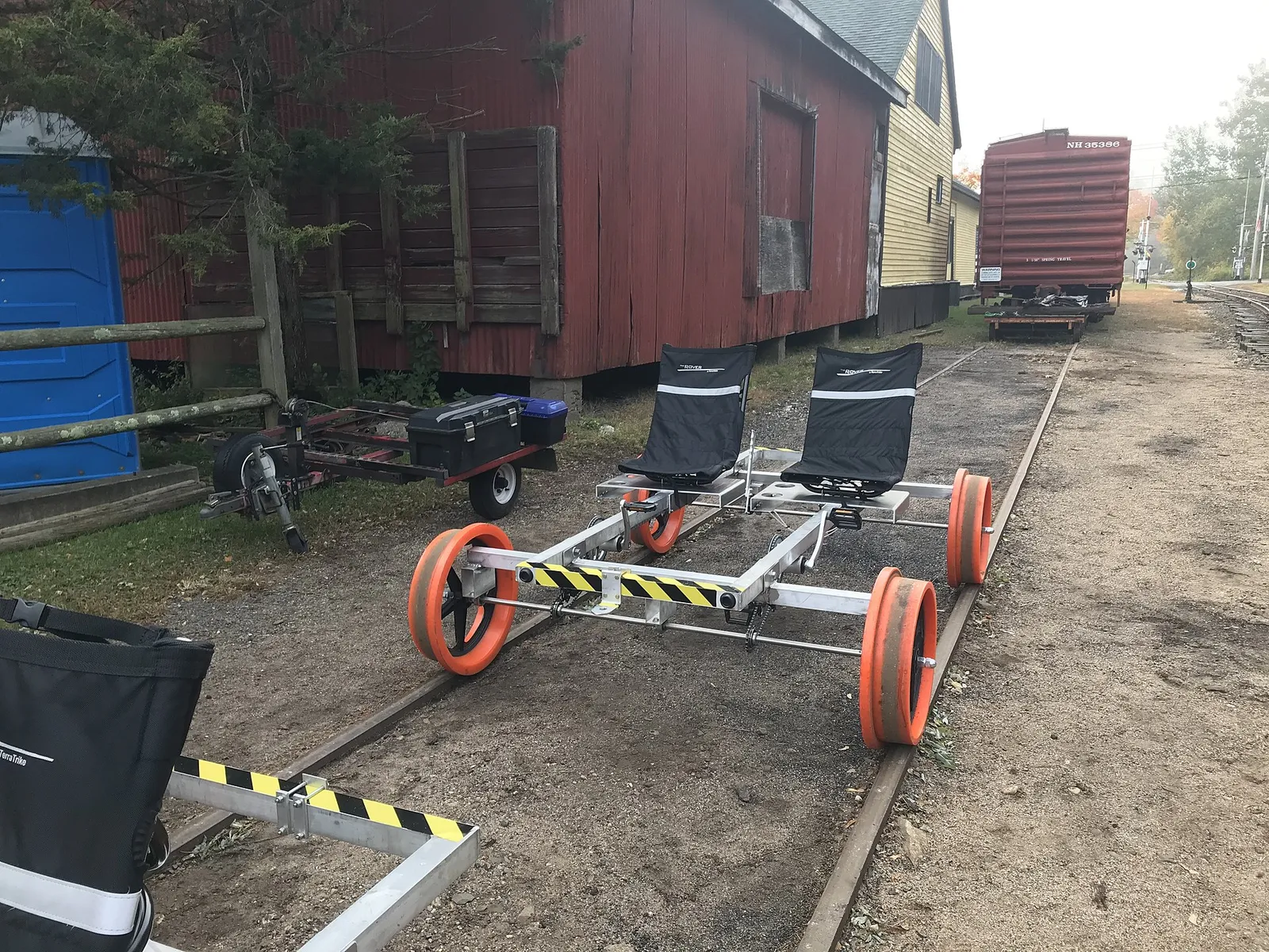A red-wheeled pedal rail bike sitting on railroad tracks