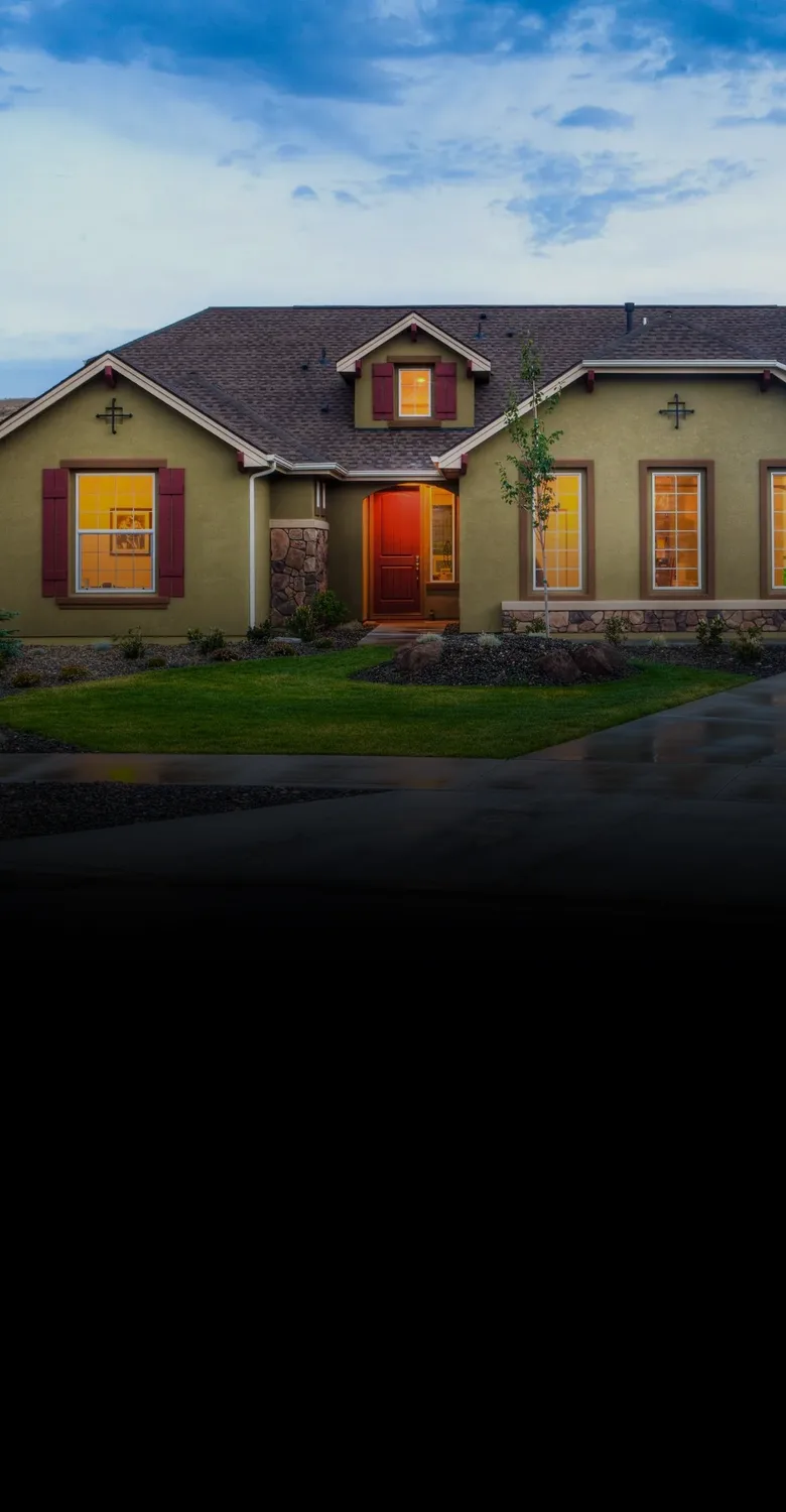 A single-level home with glowing windows at dusk, fading into a fine-line drawing of a larger home and a smaller one joined by a red arrow