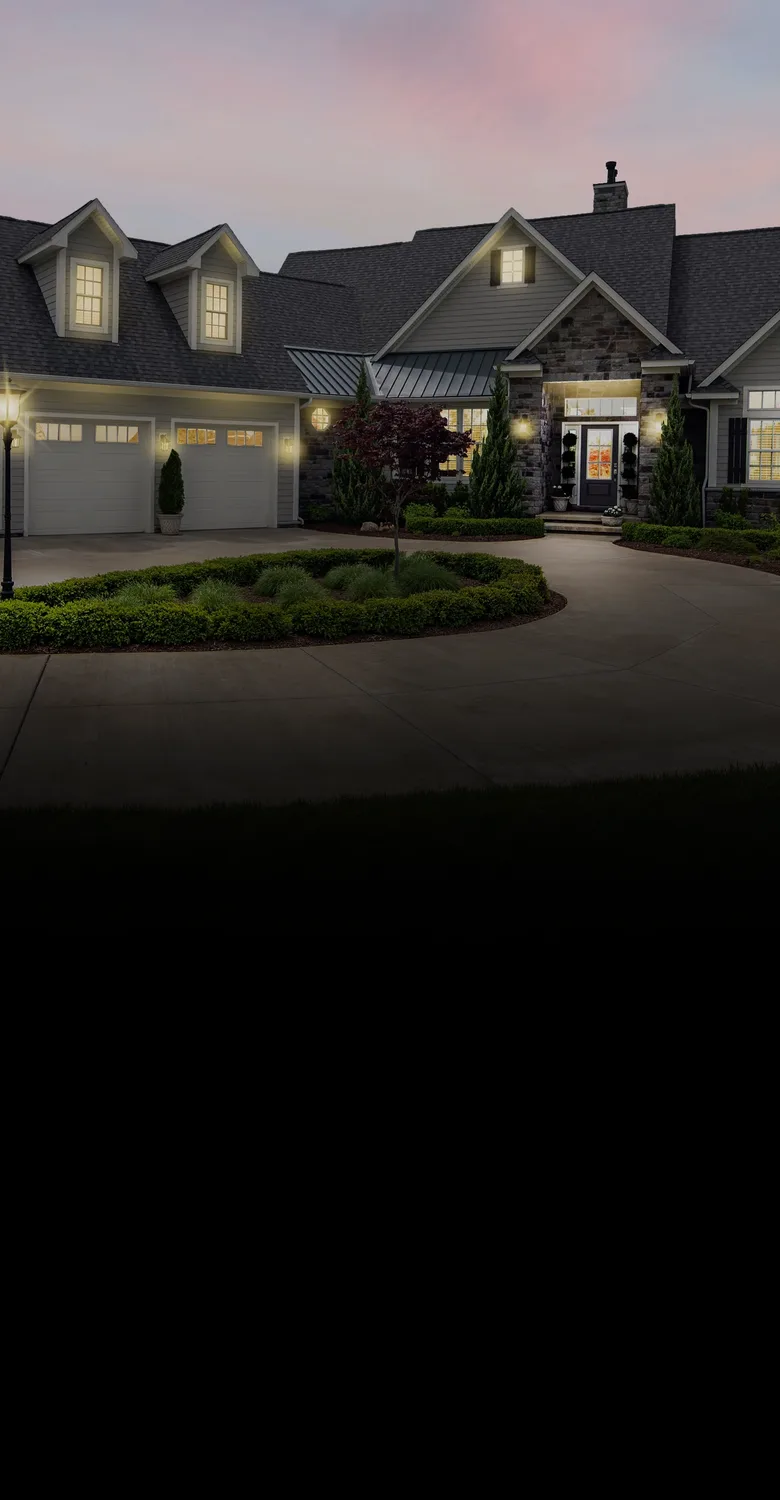 A stone-and-siding home lit up at dusk, fading into a fine-line drawing of a modern two-story home above a pool