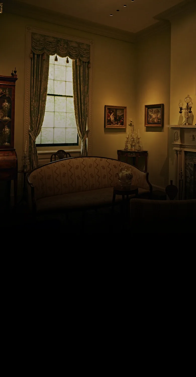 An antique-filled sitting room, fading into a fine-line drawing of a two-story home with a red seal and an old key